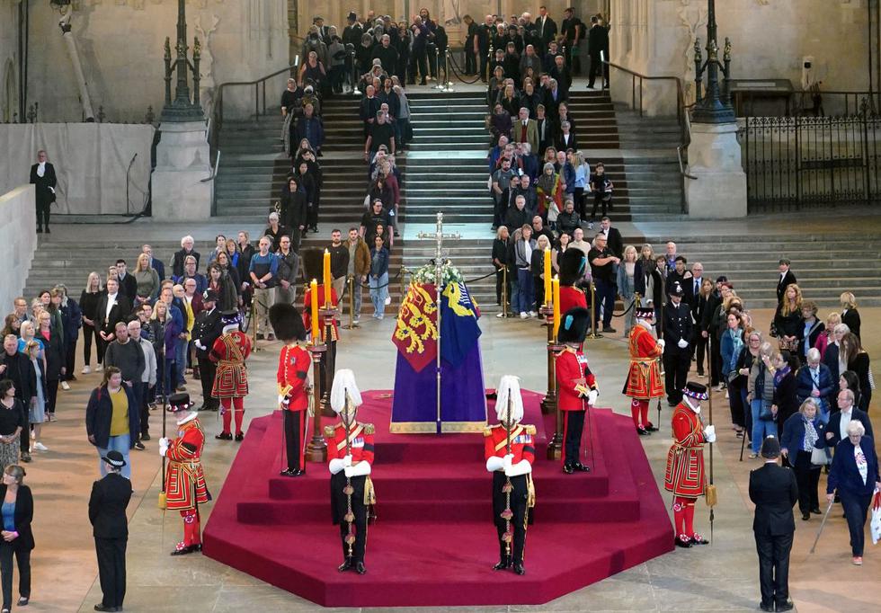 La gente desfila frente al ataúd de la reina Isabel II, envuelto en el estandarte real con la corona del Estado imperial y el orbe y el cetro del soberano, en Westminster Hall. (YUI MOK / POOL / AFP).
