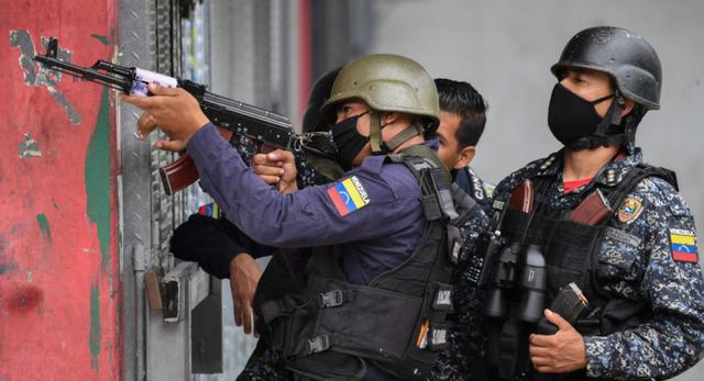 Miembros de la Policía Nacional Bolivariana apuntan a posibles objetivos luego de enfrentamientos con presuntos miembros de una banda criminal en el barrio Cota 905 de Caracas. (Foto: AFP / Federico PARRA).