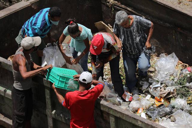 Las personas buscan comida en un contenedor de basura durante la hora de cierre en el mercado mayorista de Coche. (REUTERS/Manaure Quintero).