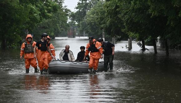 Rescatistas del Servicio Estatal de Emergencias ayudan a evacuar a un residente local de un área inundada en la ciudad de Kherson el 11 de junio de 2023. (Foto de Genya SAVILOV / AFP)