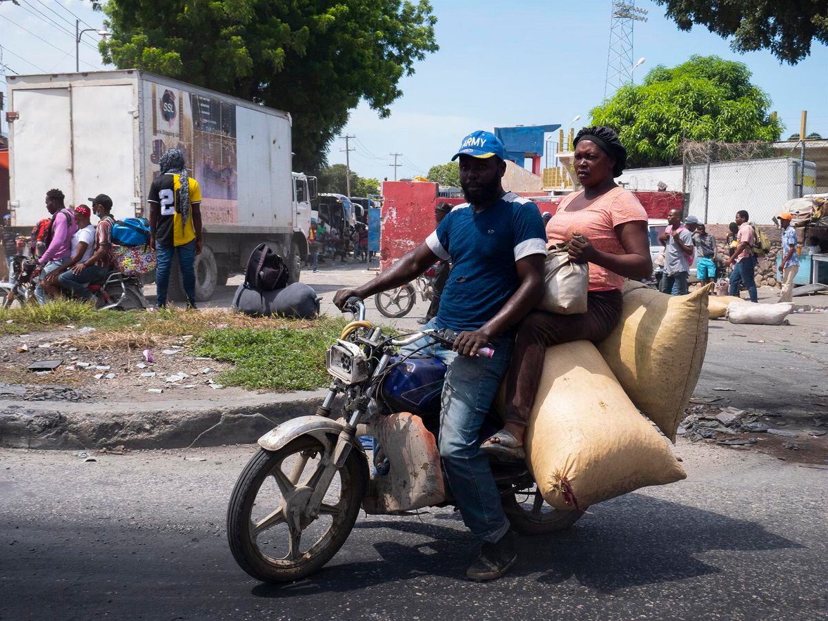 A motorcycle taxi takes a woman who bought products in a market, in Port-au-Prince, Haiti, on October 8, 2022. (Photo by Carvens Adelson / EFE)