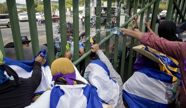Estudiantes lanzan agua contra agentes antidisturbios durante una protesta en la Universidad Centroamericana (UCA), en Managua (Nicaragua). (Foto: EFE)