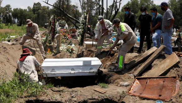 Los familiares miran a los trabajadores del cementerio que llevan el ataúd que contiene el cuerpo de Epifanio Morales que murió de la enfermedad del coronavirus (COVID-19), en una tumba en el cementerio de San Lorenzo Tezonco en la Ciudad de México. (Foto: REUTERS / Carlos Jasso).