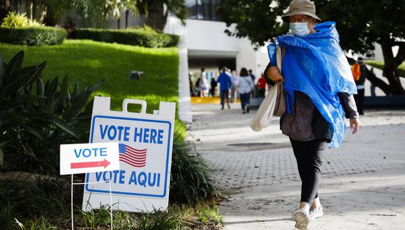 Una mujer pasa junto a un cartel de "Vote aquí" en el Ayuntamiento de Miami Beach, Florida, el 19 de octubre de 2020. (Foto de Eva Marie UZCATEGUI / AFP).