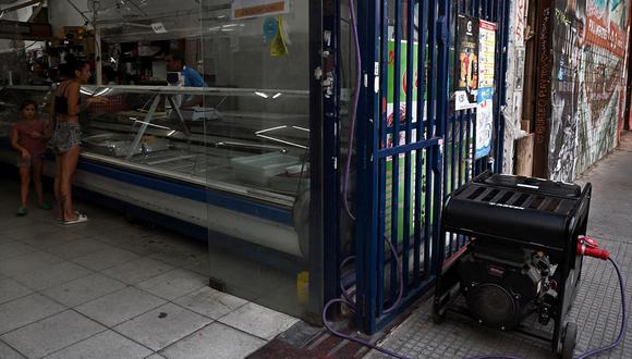 Una mujer compra en un supermercado iluminado por un generador eléctrico, en Buenos Aires el 1 de marzo de 2023, luego de un apagón provocado por un incendio que afectó el sistema de alta tensión. (Foto de Luis ROBAYO / AFP)