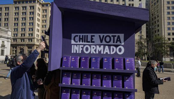 Un trabajador del gobierno, a la izquierda, junto a un stand con copias del borrador de la nueva constitución durante el lanzamiento del programa Chile Vota Informado, el miércoles 10 de agosto de 2022. (AP Foto/Esteban Félix).