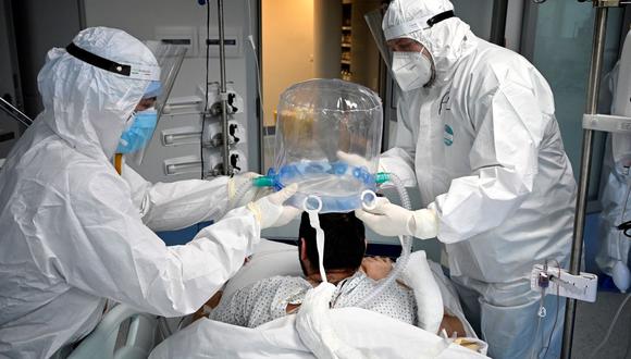 Personal médico ayuda a un paciente de coronavirus a usar una nueva tecnología no invasiva que puede reducir la necesidad de intubación en la unidad de cuidados intensivos del Instituto de Cardiología Clínica (ICC) en Roma, Italia, el 30 de diciembre de 2021. (Alberto PIZZOLI / AFP).