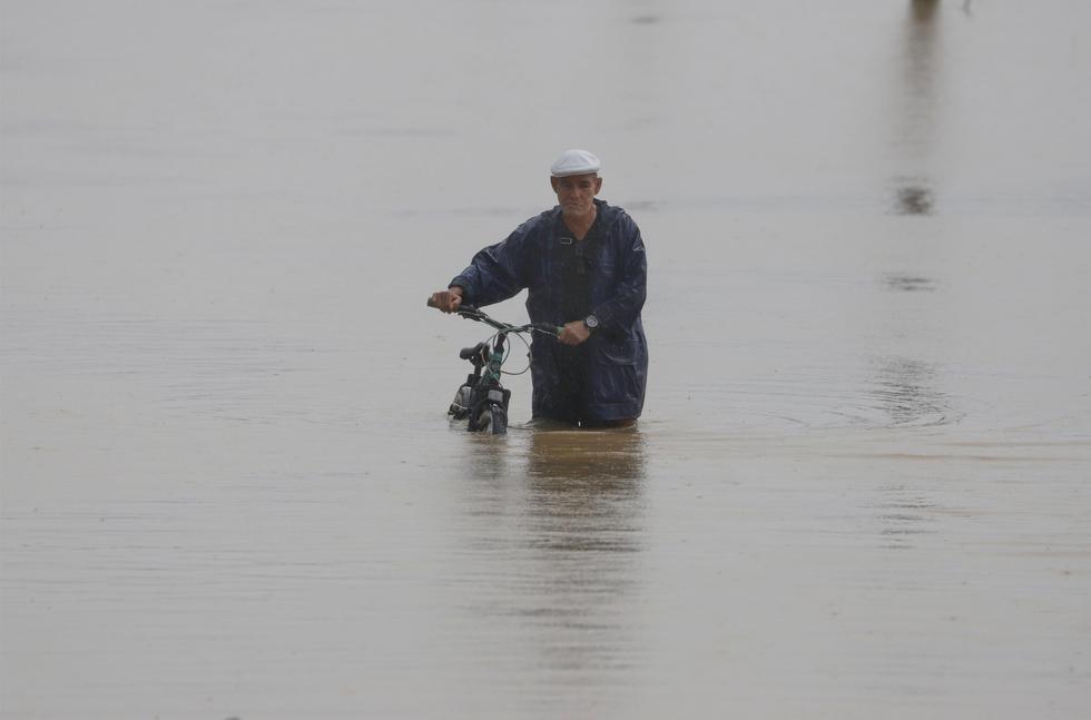 Un hombre cruza con su bicicleta una calle inundada debido a lluvias por el paso del huracán Fiona hoy, en Toa Baja (Puerto Rico). EFE/Thais LLorca