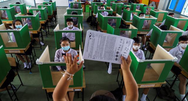 Alumnos del colegio Sam Khok, de la provincia Pathum Thani, en Tailandia, con mascarillas y protectores faciales protegidos por urnas reutilizadas mientras asisten a una clase después de que el gobierno anunciara la reapertura de las escuelas. (Foto: Reuters)