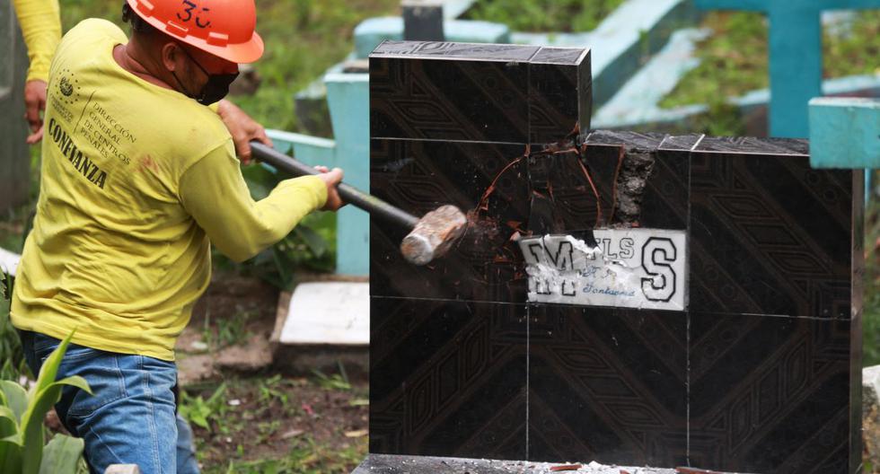 Un recluso destruye una tumba con simbología alusiva a la pandilla Mara Salvatrucha (MS-13) en un cementerio en Santa Tecla, El Salvador, el 3 de noviembre de 2022. (AFP).