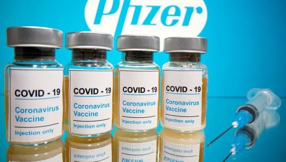 Viales con una etiqueta que dice "COVID-19 / Vacuna contra el coronavirus / Inyección solamente" y una jeringa médica frente al logotipo de Pfizer. )REUTERS / Dado Ruvic / Ilustración).