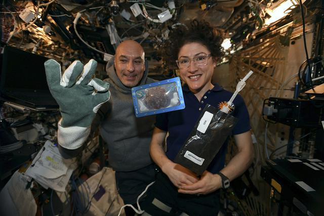 Dos astronautas sostienen la primera galleta horneada en el espacio. (Twitter | @Astro_Christina)