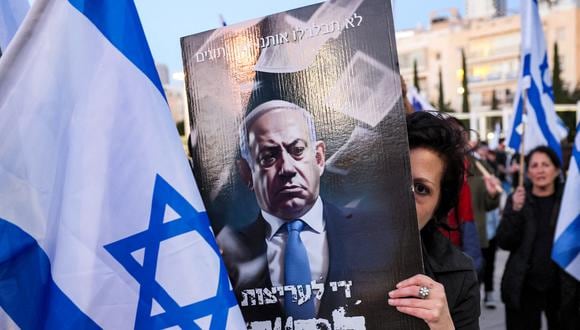 Una manifestante se cubre la cara con un cartel contra el primer ministro israelí Benjamin Netanyahu durante una marcha contra el proyecto de ley de reforma judicial del gobierno en Tel Aviv el 1 de abril de 2023. (Foto de JACK GUEZ / AFP)