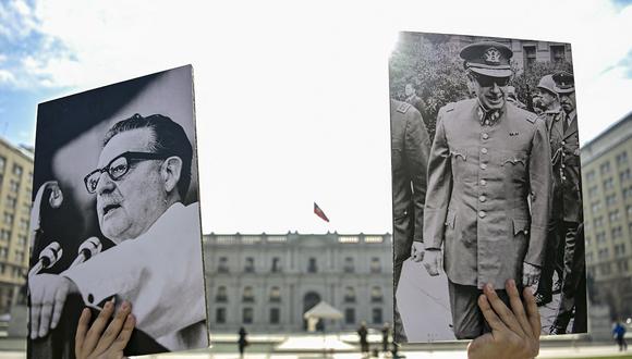 Un joven sostiene una fotografía del fallecido presidente chileno (1970-1973) Salvador Allende y del dictador chileno Augusto Pinochet afuera del Palacio Presidencial de La Moneda en Santiago, el 1 de agosto de 2023. (Foto de Martin BERNETTI / AFP)