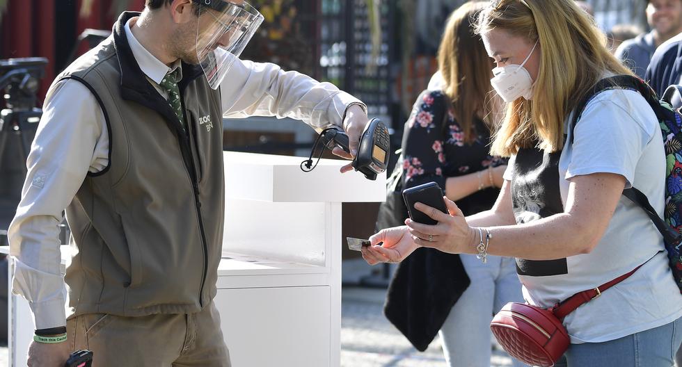 Un empleado del zoológico que llevaba un protector facial escanea los boletos de entrada en un teléfono móvil en el zoológico de Berlín, ya que reabre parcialmente para el público en medio de la nueva pandemia de coronavirus. (Foto: AFP)
