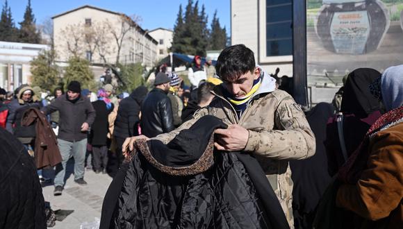 Las personas reciben ropa durante una distribución de ropa organizada por las autoridades turcas, dos días después de que un fuerte terremoto azotara la región, en la ciudad de Kahramanmaras, en el sureste de Turquía, el 8 de febrero de 2023. (Foto: OZAN KOSE / AFP)