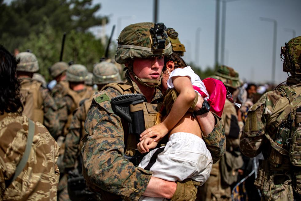 Una foto proporcionada por el Comando Central de Asuntos Públicos de los EE. UU. a través de DVIDS muestra que un infante de marina asignado a la 24.a Unidad Expedicionaria de la Infantería de Marina lleva a una niña en una puerta del Aeropuerto Internacional Hamid Karzai, en Kabul. (EFE/EPA)