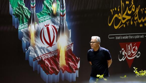 Un hombre pasa junto a una pancarta que representa misiles a lo largo de una calle de Teherán el 19 de abril de 2024. (Foto de AFP)