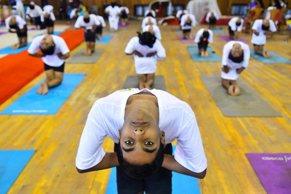 Los estudiantes realizan posturas de yoga en un estadio cubierto con motivo del Día Internacional del Yoga en Agartala, capital del estado nororiental de Tripura. (Abhisek SAHA / AFP)