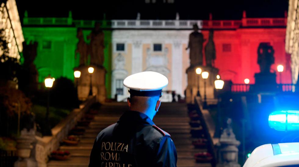 Un policía realiza su turno de guardia junto a la alcaldía de Roma, decorada con luces de los colores de Italia como símbolo de solidaridad con las víctimas del COVID-19. (Reuters)