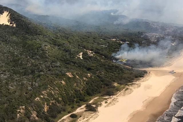 En esta foto proporcionada el 2 de diciembre de 2020, por los Servicios de Emergencia y Bomberos de Queensland, el humo sopla sobre las colinas y hacia el océano en la isla Fraser, Australia. (Queensland Fire and Emergency Services/AP).