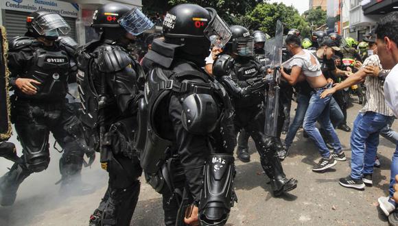 Vendedores ambulantes confrontan a miembros del Escuadrón Móvil Antidisturbios (ESMAD) luego de que no les permitieran seguir trabajando, en Cúcuta, Colombia, cerca de la frontera con Venezuela, el 29 de marzo de 2022. (Foto de Schneyder MENDOZA / AFP)
