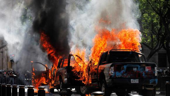 Dos patrullas arden tras ser quemadas por un grupo de manifestantes este jueves, durante una protesta por la muerte de Giovanni Lòpez, golpeado por policías de Ixtlahuacan de los Membrillos, en la ciudad de Guadalajara (México). (EFE/Francisco Guasco).