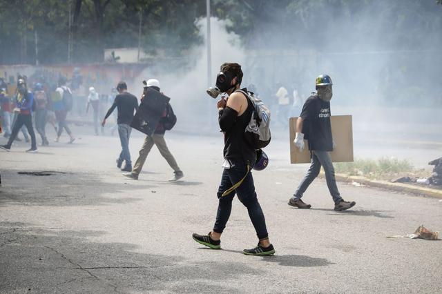 Luego, los estudiantes gritaron consignas contra el Gobierno de Nicolás Maduro e intentaron a la fuerza traspasar la barrera policial con empujones y forcejeos, pero fueron repelidos con gases lacrimógenos. (Foto: EFE)