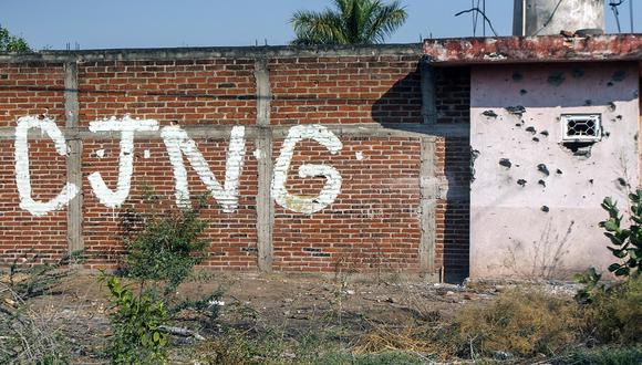 Un muro acribillado a balazos con las iniciales del grupo criminal Cartel Jalisco Nueva Generación (CJNG) en la entrada de la comunidad de Aguililla, estado de Michoacán, México, el 23 de abril de 2021. (Foto de ENRIQUE CASTRO / AFP)