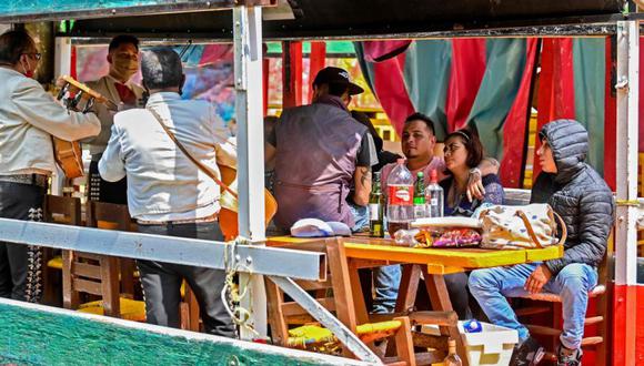 Mariachis con mascarillas para seguir los protocolos sanitarios contra el COVID-19 juegan en una trajinera en el muelle del canal Nativitas en Xochimilco, una red de canales y jardines flotantes que es una de las principales atracciones turísticas de la Ciudad de México, luego de su reapertura. (Foto: AFP / PEDRO PARDO).