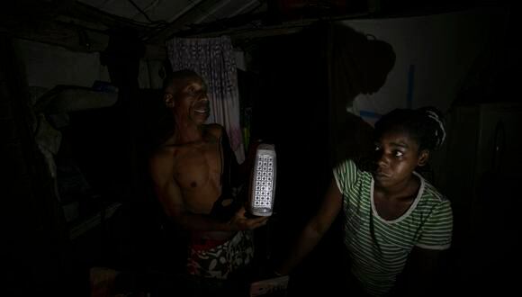 Víctor y Catalina muestran una lámpara led rota mientras hablan con EFE en su casa durante un apagón en el poblado de Santa Marta, Varadero, Cuba, el 12 de marzo del 2024. (EFE/ Yander Zamora).