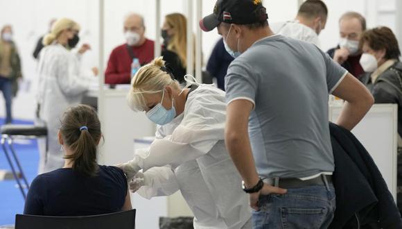Un hombre mira mientras una rusa recibe la vacuna de Johnson & Johnson contra el coronavirus COVID-19 en Zagreb, Croacia. (AP Foto/Darko Bandic).
