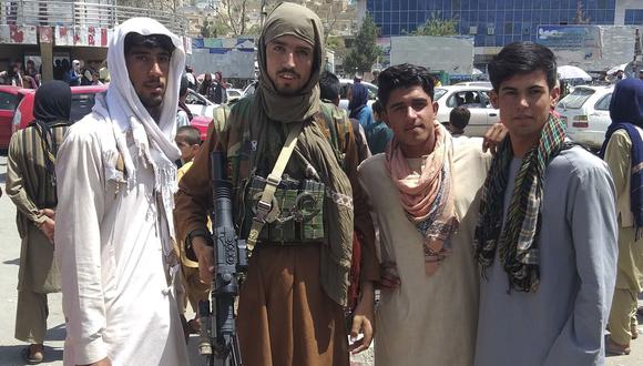 Un combatiente talibán (segundo de la izquierda) junto con los lugareños en Pul-e-Khumri el 11 de agosto de 2021. (Foto: AFP).