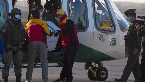 Imagen de archivo. Los trabajadores llevan una caja que contiene la vacuna contra el coronavirus Pfizer-BioNTech a un helicóptero para su distribución en el aeropuerto internacional de Santiago de Chile, el 24 de diciembre de 2020. (CLAUDIO REYES / AFP).