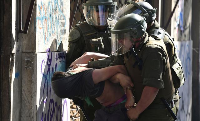 Una persona es arrestada en Santiago. (Photo by Martin BERNETTI / AFP).