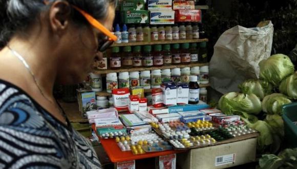 Una mujer pasa delante de un puesto de vegetales y frutas que además vende medicinas en un mercado en Rubio, Venezuela. (Foto: Reuters)