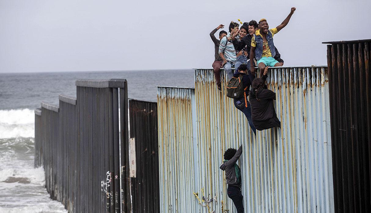 TOPSHOT - Central American migrants travelling in the "Migrant Via Crucis" caravan demonstrate at the US/Mexico Border at Tijuana's beaches, Baja California state, Mexico, on April 29, 2018.  The US has threatened to arrest around 100 Central American migrants if they try to sneak in from the US-Mexico border where they have gathered, prompting President Donald Trump to order troop reinforcements on the frontier. / AFP / GUILLERMO ARIAS