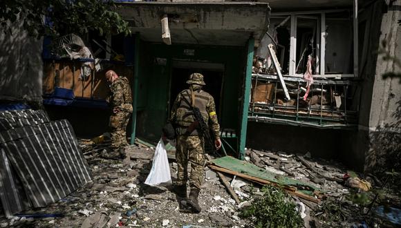 Militares ucranianos frente a un edificio de apartamentos dañado después de una huelga en la ciudad de Slovyansk. (ARIS MESSINIS / AFP)
