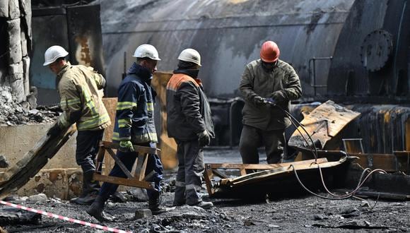 Los rescatistas y trabajadores limpian los escombros en una sala de turbinas llena de equipos quemados en una planta de energía destruida después de un ataque ruso en Ucrania el 19 de abril de 2024. (Foto de Genya SAVILOV / AFP).