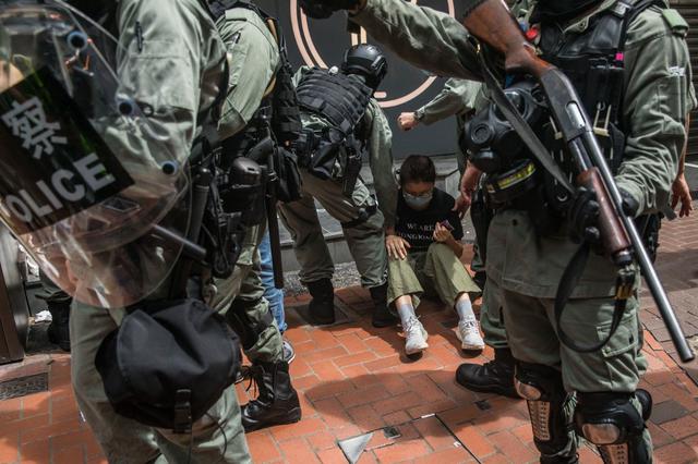 La policía antidisturbios detiene a una mujer mientras retira a los manifestantes que participan en una protesta contra la nueva ley de seguridad nacional china para Hong Kong. (DALE DE LA REY / AFP)