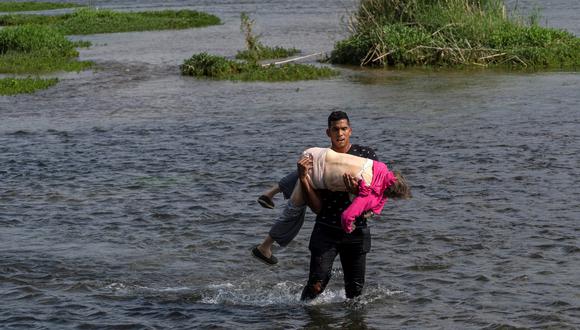 Un muchacho venezolano carga a una mujer de la tercera edad para ayudarla a atravesar el Río Grande, en la frontera de México y Estados Unidos. REUTERS