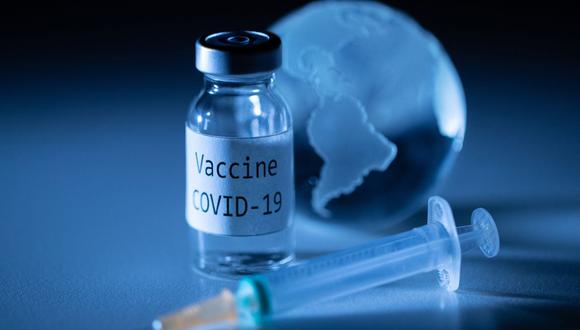 Una fotografía ilustrativa tomada el 19 de noviembre de 2020 muestra un vial con la etiqueta adhesiva de la vacuna coronavirus Covid-19, una jeringa y un globo terráqueo. (Foto de JOEL SAGET / AFP).