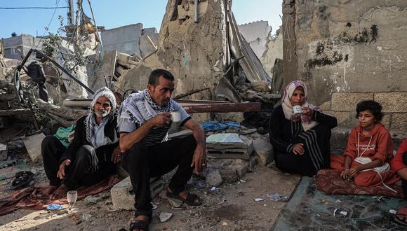 Amal al-Robayaa, su esposo Imed y su padre Salman beben té entre los escombros de un edificio destruido por el bombardeo israelí en Rafah, en el sur de la Franja de Gaza, el 7 de noviembre de 2023. (Foto de SAID KHATIB / AFP)