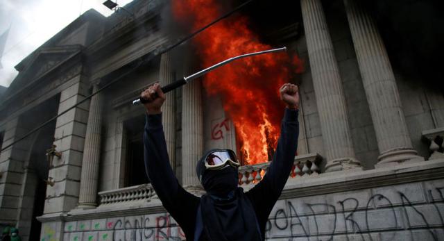 Un hombre protesta en frente del Congreso de Guatemala en llamas ocasionado por manifestantes que protestan contra del Gobierno del presidente, Alejandro Giammattei hoy en Ciudad de Guatemala (Guatemala). (EFE/Esteban Biba).