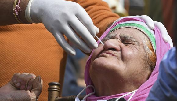 Un trabajador de la salud toma una muestra de un hisopo nasal de una mujer para realizar la prueba del coronavirus en Srinagar (India), el 21 de abril de 2021. (TAUSEEF MUSTAFA / AFP).