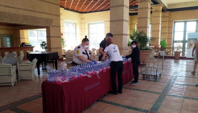 Empleados colocan botellas de agua  sobre una mesa en el hotel de Tenerife tras confirmarse caso de coronavirus. (Reuters).
