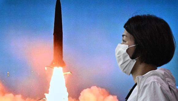 Una mujer pasa frente a una pantalla que muestra una transmisión de noticias con imágenes de archivo de una prueba de misiles de Corea del Norte, en una estación de tren en Seúl el 5 de junio de 2022. (Anthony WALLACE / AFP).