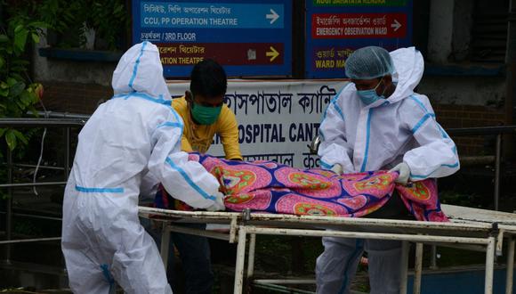 Los trabajadores del hospital que llevan equipo de protección personal (equipo de protección personal) llevan el cadáver de una persona en el hospital del distrito de Siliguri (India), el 12 de mayo de 2021. (Diptendu DUTTA / AFP).