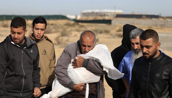 Un pariente lleva el cuerpo de un niño durante el funeral de los miembros de la familia Seyam, que murieron en un ataque de Israel en Khan Yunis, en el sur de la Franja de Gaza, el 22 de noviembre de 2023. (Foto de MAHMUD HAMS / AFP).