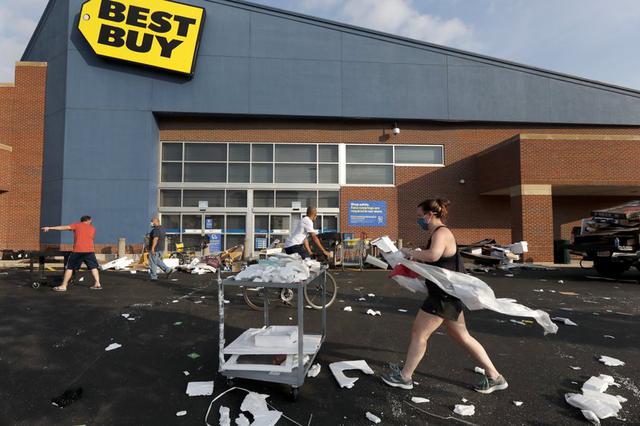 Un grupo de personas ayuda a limpiar el estacionamiento de una tienda Best Buy que fue saqueada en la noche en Chicago, Estados Unidos. (Foto AP / Charles Rex Arbogast).